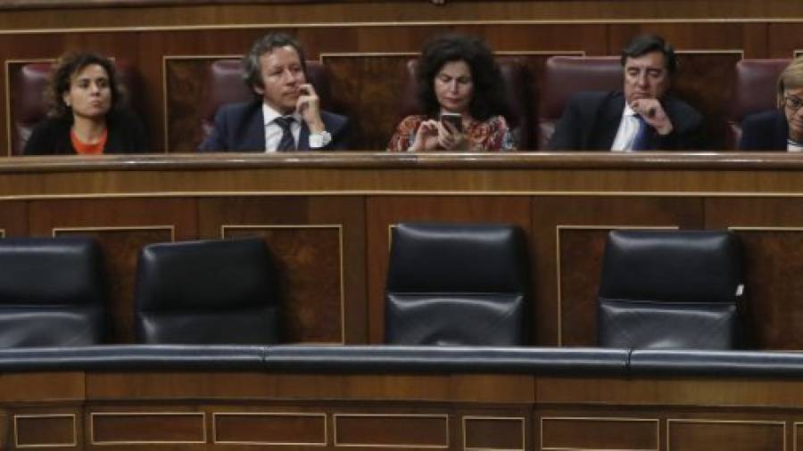 El ministro del Interior, Jorge Fernández Díaz, comunica un mensaje ´secreto´ al presidente del Gobierno, Mariano Rajoy, con cuatro sillones de ministro por medio. Foto: EFE