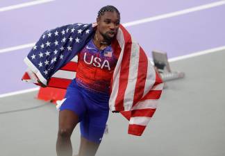 Noah Lyles, con la bandera de los Estados Unidos, tras su victoria. Foto: EFE