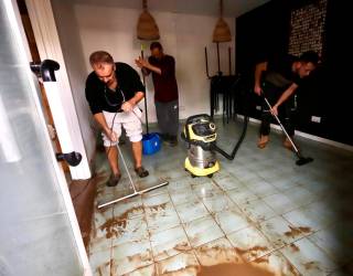 Algunos bajos y locales achicando agua de la tormenta de este lunes. Foto: Marc Bosch