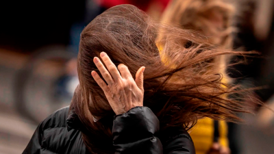 Una mujer intenta quitarse el cabello de la cara empujado por el viento. Foto: EFE