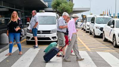 Pasajeros en la zona de llegadas del Aeropuerto de Reus, donde esperan los taxis, este junio. Foto: Alfredo González
