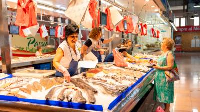 Clientela haciendo la compra en la pescadería Toni Ortiz, uno de los doce negocios del Mercat del Carrilet, hoy. Foto: Alba Mariné