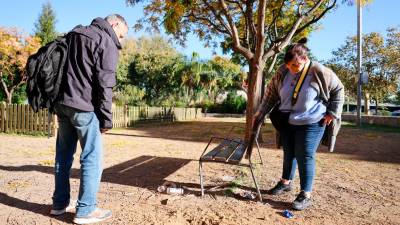 El president i la vicepresidenta de l’Associació de Veïns den Defensa del Parc de Mas Iglesias i Barri, mostrant les restes d’ampolles al voltant d’un banc. Foto: Alba Mariné