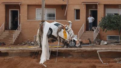 Un vehículo empotrado cotra un poste de luz frente a una serie de viviendas en Paiporta, este viernes. Foto: EFE