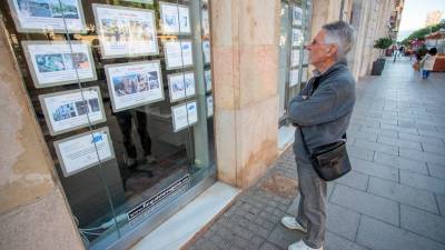 Un ciudadano mira la oferta de pisos en venta y alquiler en una inmobiliaria de Tarragona. FOTO: marc bosch