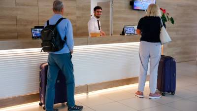 Imagen de dos turistas en la recepción de un hotel. Foto: Alba Mariné