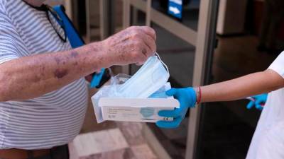 Una trabajadora de un centro de salud entrega una mascarilla a un paciente. Foto: EFE