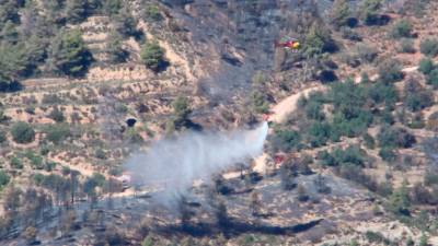 Un helicóptero descarga agua en una zona forestal en Cabacés. Foto: ACN