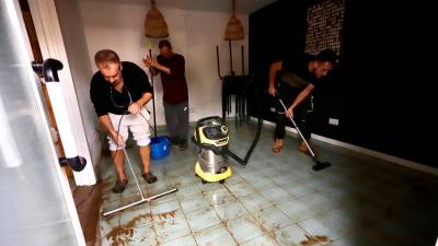 Algunos bajos y locales achicando agua de la tormenta de este lunes. Foto: Marc Bosch