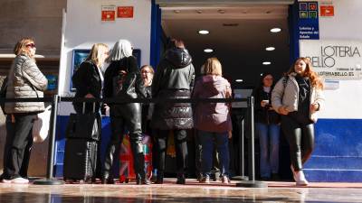 Varias personas hacen cola en una administración de lotería durante este viernes. Foto: EFE