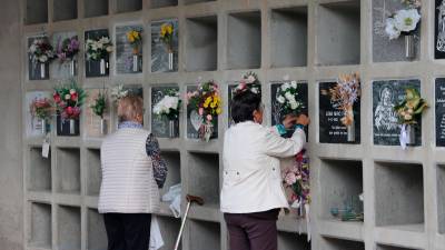 Dos señoras llevan flores en homenaje a sus difuntos en el cementerio de Montgat durante el día de Tots Sants. Foto: ACN