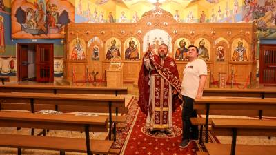 Padre Vasile Baltaretu, junto a su hijo, en el interior de la parroquia ortodoxa de San Jerarca Calínico y San Fructuoso. FOTO: Alba Mariné