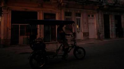 Fotografía de archivo que muestra a un bicitaxi que transita por una calle poco iluminada en La Habana (Cuba). Foto: EFE