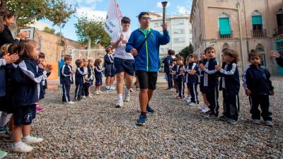 Un dels esportistes en primer terme, amb la torxa, aquest dijous 17 d’octubre a l’Escola Maria Cortina. Foto: Marc Bosch