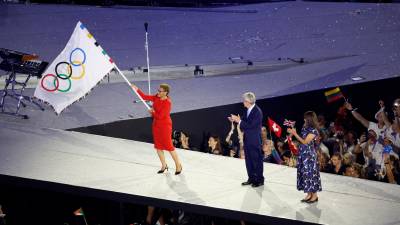 La alcaldesa de Los Angeles, Karen Bass (i), ondea la bandera olímpica, junto al presidente del COI, Thomas Bach. Foto: EFE