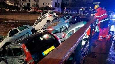 Imagen de los coches arrastrados por el agua atorados en un puente. Foto: Bombers