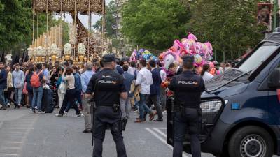 Dos agentes de la Policía Nacional vigilan el paso de un misterio de Semana Santa, en plena alerta, ayer en Sevilla. FOTO: Julio Muñoz/EFE