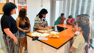 La regidora Anabel Martínez acompanya les monitores i els nens, que aprenen a fer croissants al Centre Cívic Migjorn de Reus. FOTO: Alfredo González