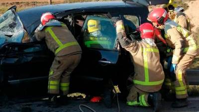 Varios bomberos ayudan a sacar a la persona atrapada en el accidente de tráfico. Foto: Bombers