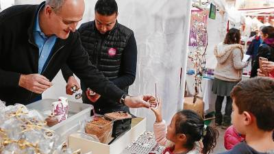 Antonio Sirvent entrega un helado de Navidad a una de las niñas que hizo cola para probar este postre en el estand de la heladería en el mercadillo que se organiza en la plaza de la Vila. FOTO: FABIÁN ACIDRES