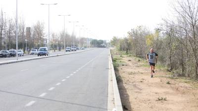 Un ‘runner’ corre por el tramo de tierra de la parte norte del Vial del Cavet, donde en un año empezarán a hacer la nueva acera. FOTO: ALBA MARINÉ