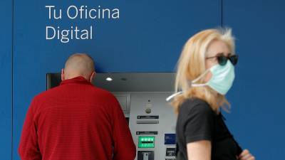 Dos personas, frente al cajero automático de un banco.  FOTO: EFE