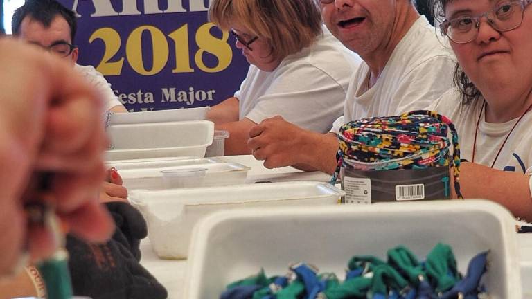 Miembros de la Fundaci&oacute; Santa Teresa en la confecci&oacute;n de las pulseras. FOTO: VICTOR MERENCIO