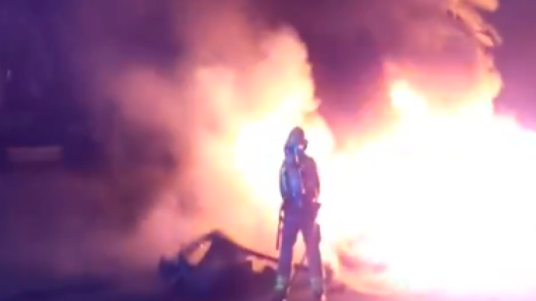 Un bombero apagando un incendio de contenedor.