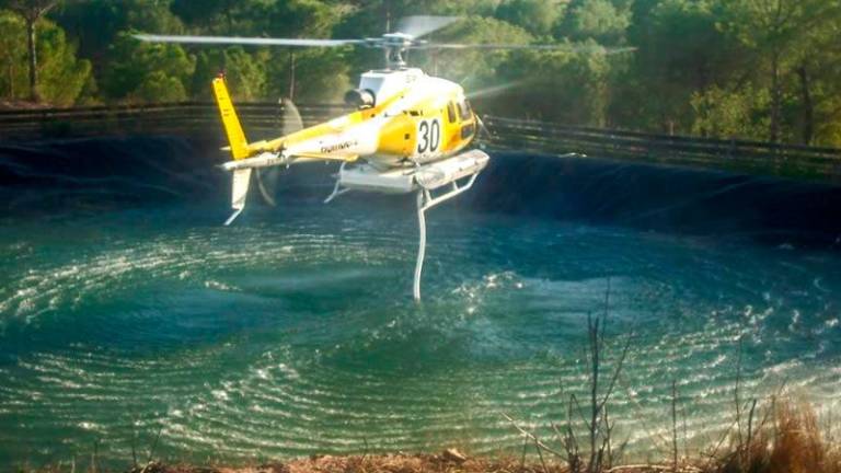 $!Un helicóptero de extinción carga agua en una balsa antiincendios.