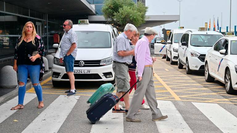 Pasajeros en la zona de llegadas del Aeropuerto de Reus, donde esperan los taxis, este junio. Foto: Alfredo González