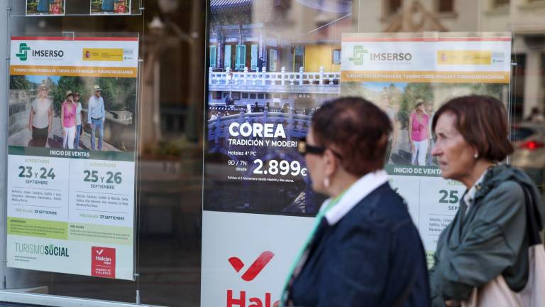 Dos jubiladas pasan por delante de una agencia de viajes donde anuncia viajes del Imserso en Bilbao. FOTO: EFE