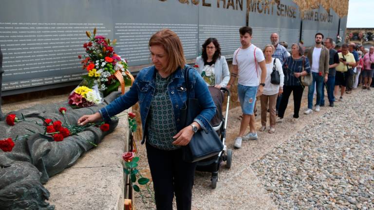 Una dona col·loca una ofrena floral al conjunt escultòric ‘Dignitat’ a una de les fosses comunes del cementiri de Tarragona. Foto: Ariadna Escoda