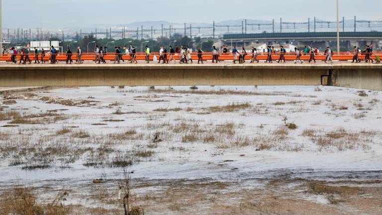 Personas cruzando el puente que separa la ciudad de Valencia de los municipios de la comarca vecina de l’Horta Sud afectados por la DANA. Foto: EFE