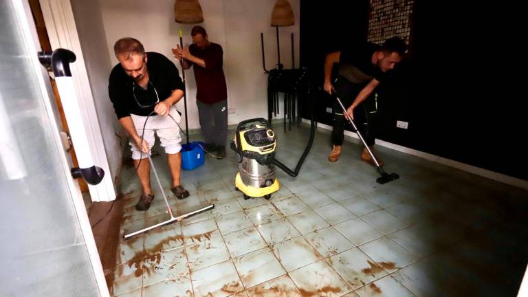 Algunos bajos y locales achicando agua de la tormenta de este lunes. Foto: Marc Bosch