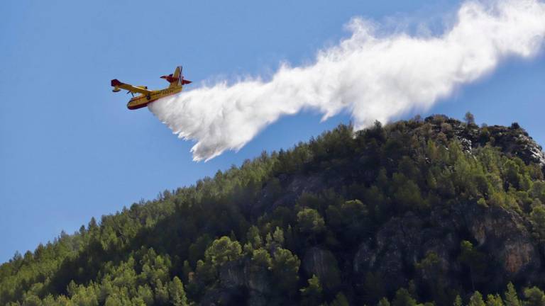 $!Un hidroavión descargando agua en el flanco izquierda del incendio de Cabacés, justo delante del municipio. FOTO: Marc Bosch