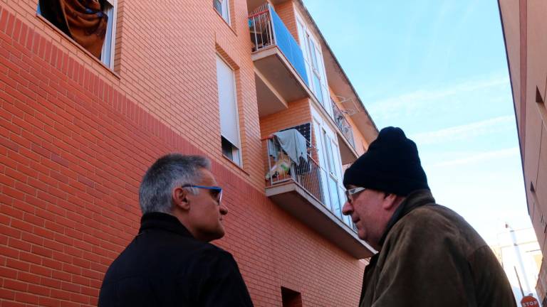 Marcel·lí Balcells, propietari d’un pis d’un bloc ocupat de Santa Bàrbara d’on ha hagut de marxar, acompanyat d’un amic davant de l’edific ocupat i amb panells solars. Foto:: ACN