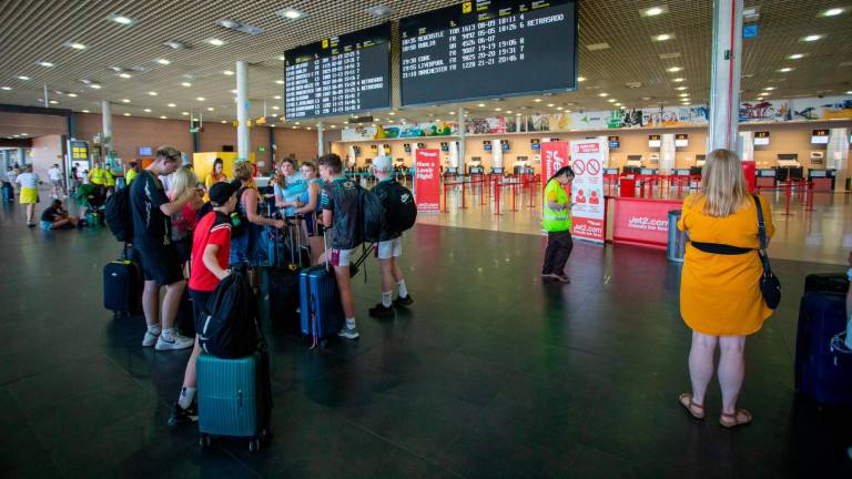 Pasajeros en el aeropuerto atentos, este sábado, al panel informativo que mostró vuelos retrasados. Foto: M. Bosch
