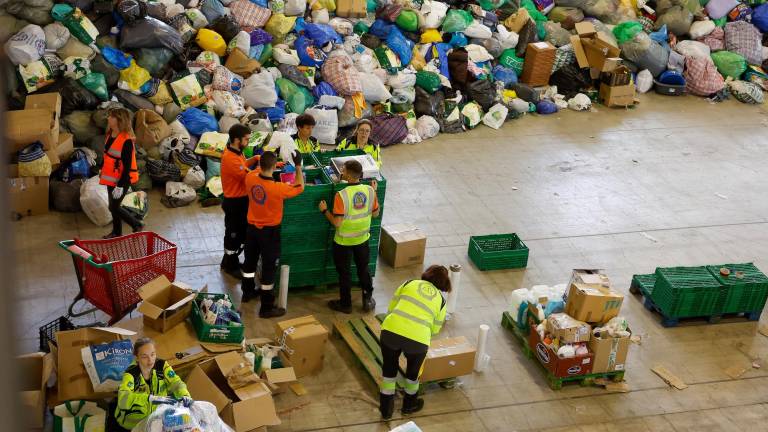 Varias personas colocan y organizan la ayuda recogida para los afectados de la DANA en el Ferial de Casa de Campo en Madrid. Foto: EFE