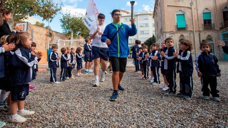 Un dels esportistes en primer terme, amb la torxa, aquest dijous 17 d’octubre a l’Escola Maria Cortina. Foto: Marc Bosch