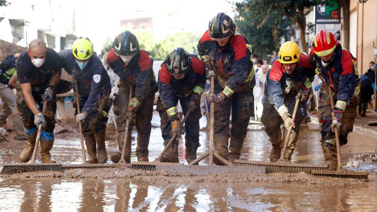 Decenas de voluntarios continuan extrayendo lodo de las calles en Catarroja. Foto: EFE