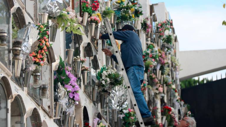 Un señor lleva flores a un nicho del cementerio de Montgat en el día de Tots Sants. Foto: ACN