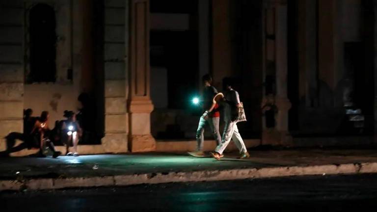 Varias personas caminan por una calle sin iluminación en La Habana, en una imagen de archivo. Foto: EFE