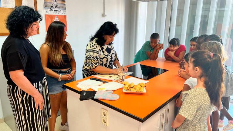 La regidora Anabel Martínez acompanya les monitores i els nens, que aprenen a fer croissants al Centre Cívic Migjorn de Reus. FOTO: Alfredo González