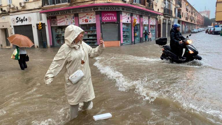 Una mujer hace fotos con el agua hasta las rodillas en Málaga donde las fuertes trombas de agua y granizo que se registran este miércoles han causado inundaciones y la acumulación de grandes balsas en algunas de las principales avenidas de todos los distritos de la ciudad. Foto: EFE