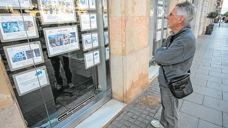 Un ciudadano mira pisos en venta y en alquiler ante una inmobiliaria. Foto: Marc Bosch/DT