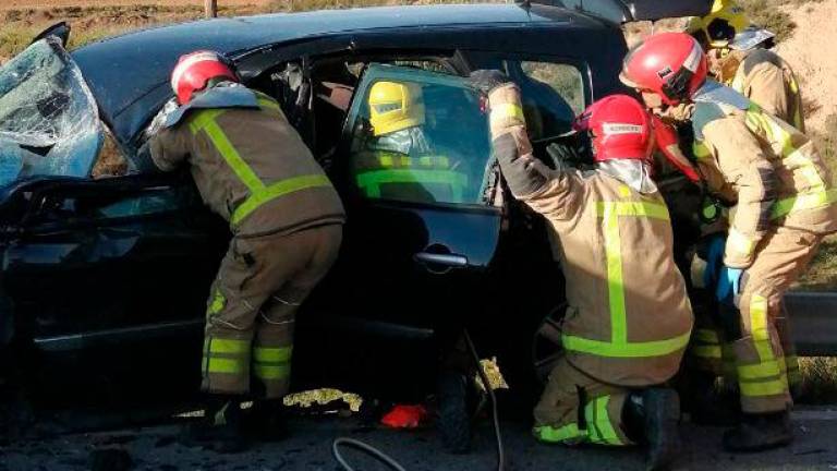 Varios bomberos ayudan a sacar a la persona atrapada en el accidente de tráfico. Foto: Bombers