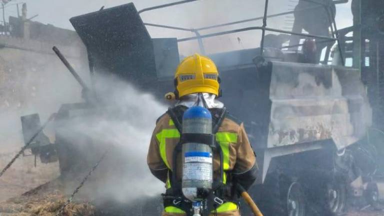 $!Un bombero apagando la máquina agrícola, que ha quedado calcinada. Foto: DT