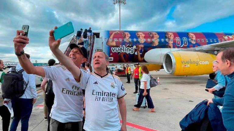 Dos seguidores del Real Madrid se fotografían con el avión de Vueling logotipado con las jugadoras del Barça. FOTO: TWITTER