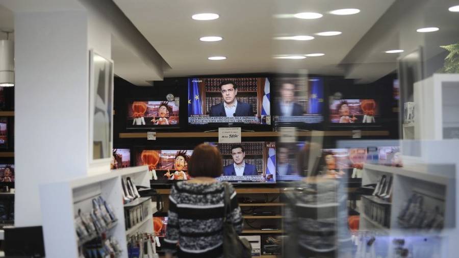 Una mujer observa en una tienda el discurso televisado del primer ministro griego, Alexis Tsipras. Foto: F. Plegas