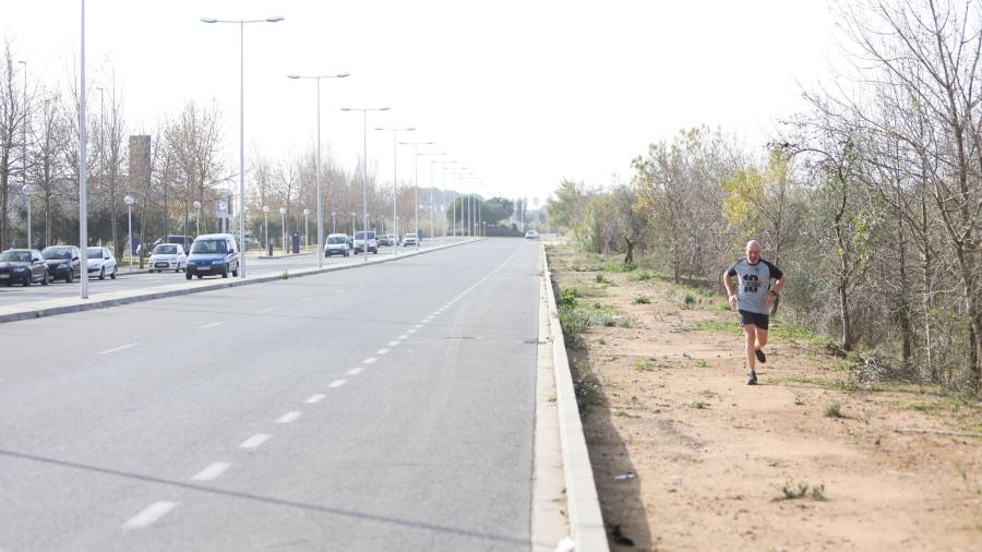 Un ‘runner’ corre por el tramo de tierra de la parte norte del Vial del Cavet, donde en un año empezarán a hacer la nueva acera. FOTO: ALBA MARINÉ